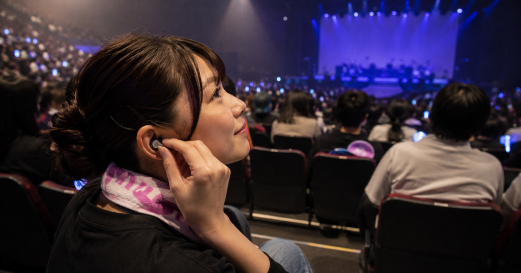 ライブ会場の開演前、客席でライブ用耳栓を装着している参加者の様子